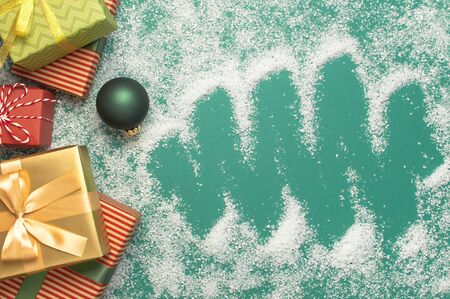 Flat lay Xmas holiday 2020 celebration. New Year Christmas presents, Christmas balls, holiday flashlight on green background with snow top view. Gift boxes greeting card Festive decorations.の写真素材