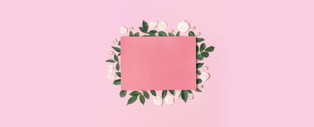 Flowers composition. Pink blank paper, white fresh roses and green leaves on gentle pink background. Flat lay, top view, copy space. Flower card, greeting, holiday mockup. Valentine's Day background.の写真素材
