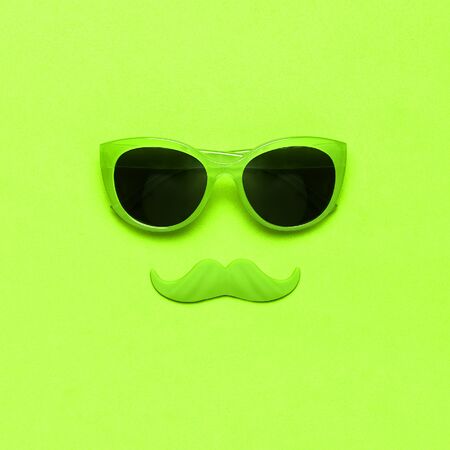 Creative party decoration concept. Green mustache, Sunglasses, props for photo booths, carnival parties on green background top view flat lay copy space. Father's day, Men's health awareness month.の写真素材