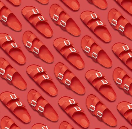 Pattern of Fashionable beach coral sandals on bright coral background. Flat lay top view copy space. Creative beach concept, stylish summer shoes, vacation, travel. Trend coral color.の写真素材