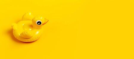 Creative summer beach concept. Inflatable mini yellow chicken or duckling on yellow background, pool float party. Flat lay copy space. Trend Inflatable Children toy for swimming. Layout for design.の写真素材
