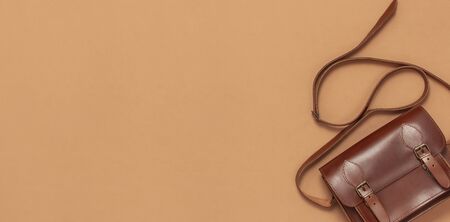 Brown leather women bag on brown beige background top view flat lay copy space. Fashionable women's accessories. Sales Fashion Concept. Stylish Lady Clothes. Luxury Leather Bag. Shopping.の写真素材