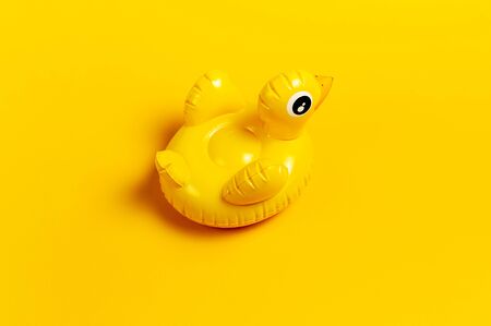 Creative summer beach concept. Inflatable mini yellow chicken or duckling on yellow background, pool float party. Flat lay copy space. Trend Inflatable Children toy for swimming. Layout for design.の写真素材