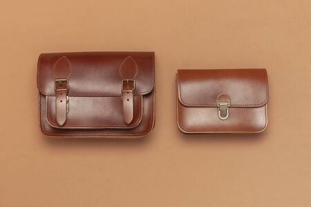 Two Brown leather women bag on brown beige background top view flat lay copy space. Fashionable women's accessories. Sales Fashion Concept. Stylish Lady Clothes. Luxury Leather Bag. Shopping.の写真素材