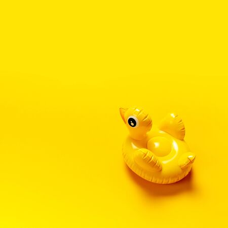 Creative summer beach concept. Inflatable mini yellow chicken or duckling on yellow background, pool float party. Flat lay copy space. Trend Inflatable Children toy for swimming. Layout for design.の写真素材