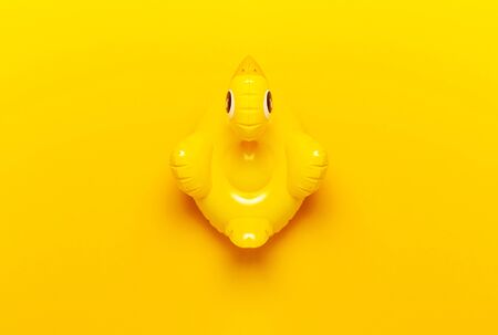 Creative summer beach concept. Inflatable mini yellow chicken or duckling on yellow background, pool float party. Flat lay copy space. Trend Inflatable Children toy for swimming. Layout for design.の写真素材