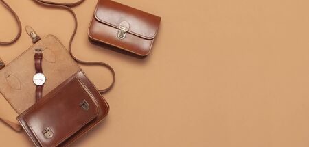 Brown leather women bag, stylish wristwatch on brown beige background top view flat lay copy space. Fashionable women's accessories. Sales Fashion Concept. Stylish Lady Clothes. Luxury Leather Bag.の写真素材