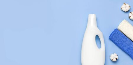 White plastic packaging of laundry detergent, liquid powder, washing conditioner, towels and cotton flowers on blue background. Flat lay top view copy space. Bio organic product. Eco cleaning concept.の写真素材