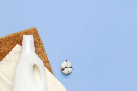 White plastic packaging of laundry detergent, liquid powder, washing conditioner, towels and cotton flowers on blue background. Flat lay top view copy space. Bio organic product. Eco cleaning concept.の写真素材