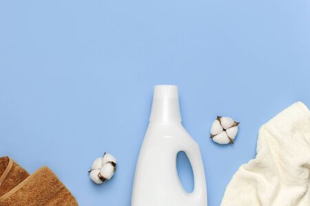 White plastic packaging of laundry detergent, liquid powder, washing conditioner, towels and cotton flowers on blue background. Flat lay top view copy space. Bio organic product. Eco cleaning concept.の写真素材