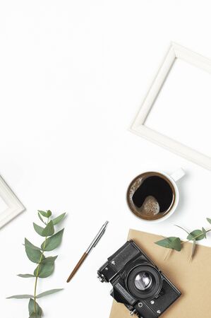 Photo frame old retro camera notebook diary cup of coffee pens eucalyptus leaves on white background. Flat lay top view copy space. Stylish minimal composition artwork mockup Feminine desk workspace.の写真素材