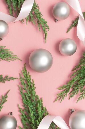 Silver Christmas toy balls, holiday ribbons, christmas tree branches on pink background. Flat lay, top view, copy space. New Year's composition, winter decoration. Minimal celebration concept.の写真素材