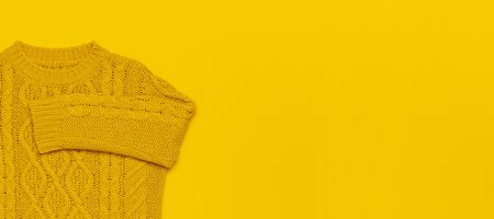 Autumn flat lay composition. Orange yellow knitted woolen female sweater on yellow background top view copy space. Fashionable women's fall winter accessories. Cozy Knit Jumper Stylish Lady Clothes.の写真素材