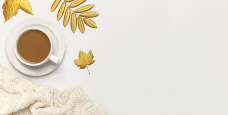 White cup with coffee, golden autumn leaves, knitted plaid on light background top view flat lay. Composition with cup of morning coffee, hot autumn drink Fall concept Autumn background Cozy breakfast.の写真素材
