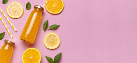 Flat lay composition with glass bottles of juice or fresh, slices of fresh lemon and orange, green leaves, cocktail tubes on pink background top view copy space. Citrus Juice Concept Vitamin C Fruits.の写真素材