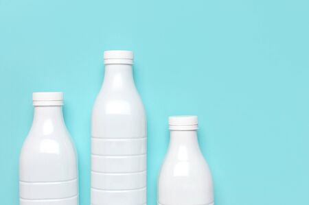 White plastic bottle containers for dairy products on blue turquoise background top view flat lay. Plastic Kefir Yogurt Milk Bottle. Packaging template mockup. Layout for your design.の写真素材