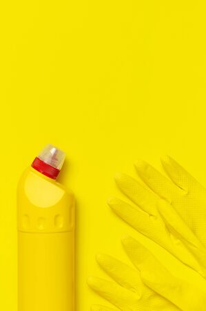 House cleaning concept. Household chemicals, disinfectant, bleach, antibacterial gel, yellow rubber gloves, sponge, rags on yellow background. Flat lay top view copy space. Cleaning accessories.の写真素材