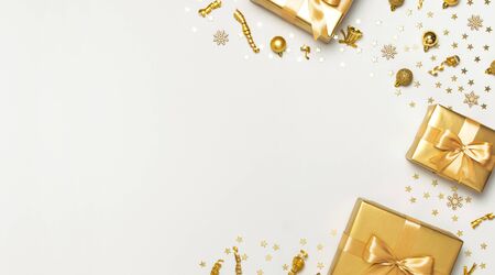 Merry Christmas and Happy Holidays greeting card. Beautiful golden gift balls ribbons confetti stars on gray background top view Flat lay. New Year presents Festive decorations party 2020 celebration.の写真素材