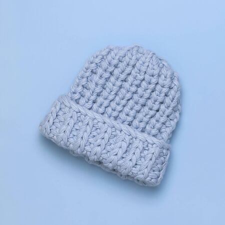 Flat lay fashionable blue knitted winter hat for women on blue background top view. Stylish woolen hat, concept of winter accessories for the cold. Advertising, shopping, winter sale.の写真素材