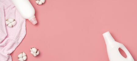 White plastic packaging of laundry detergent, liquid powder, washing conditioner, towels and cotton flowers on pink background. Flat lay top view copy space. Bio organic product. Eco cleaning concept.の写真素材