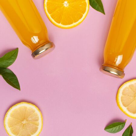 Flat lay composition with glass bottles of juice or fresh, slices of fresh lemon and orange, green leaves, cocktail tubes on pink background top view copy space. Citrus Juice Concept Vitamin C Fruits.の写真素材