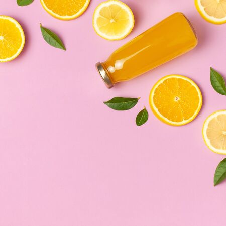 Flat lay composition with glass bottles of juice or fresh, slices of fresh lemon and orange, green leaves, cocktail tubes on pink background top view copy space. Citrus Juice Concept Vitamin C Fruits.の写真素材