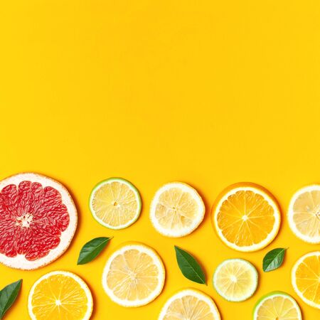 Flat lay composition with slices of fresh lemon orange grapefruit lime green leaves on yellow background top view copy space. Citrus Juice Concept, Vitamin C, Fruits. Creative summer background.の写真素材