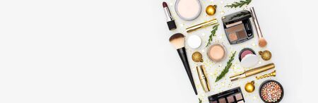 Makeup mascara foundation cream lipstick eyeshadow blush balls and New Year decorations gold Christmas balls confetti stars fir branches on light background Flat lay top view. Cosmetics, holiday Xmas.の写真素材