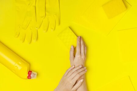 House cleaning concept. Household chemicals, disinfectant, bleach, antibacterial gel, yellow rubber gloves, sponge, rags on yellow background. Flat lay top view copy space. Cleaning accessories.の写真素材