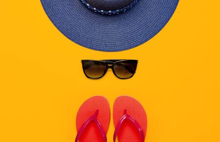 Summer beach sea accessories. Coral flip flops, blue straw hat, sunglasses, shells, starfish on yellow background top view flat lay copy space. Summer background. Holiday vacation travel concept.の写真素材