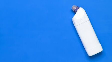 White plastic bottle for liquid detergent, cleaning agent, bleach, antibacterial gel with natural plant extract and green leaves on blue background. Eco style cleaning concept. Flat lay top view.の写真素材