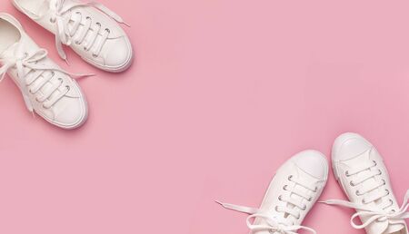 White female fashion sneakers on pink background. Flat lay, top view, copy space. Women's shoes. Stylish white sneakers. Fashion blog or magazine concept. Minimalistic shoe background, sport shoes.の写真素材