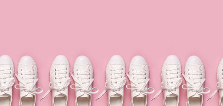White female fashion sneakers on pink background. Flat lay, top view, copy space. Women's shoes. Stylish white sneakers. Fashion blog or magazine concept. Minimalistic shoe background, sport shoes.の写真素材