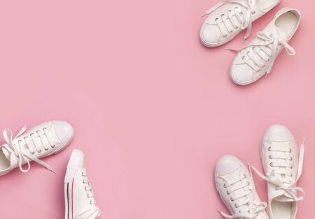 White female fashion sneakers on pink background. Flat lay, top view, copy space. Women's shoes. Stylish white sneakers. Fashion blog or magazine concept. Minimalistic shoe background, sport shoes.の写真素材
