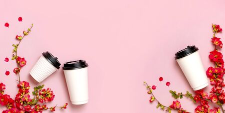 Coffee or tea paper cup, spring branches of red flowers on pink background top view flat lay copy space. Take away coffee cup, mockup. Spring coffee concept, layout for design. Spring flowering.の写真素材