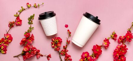 Coffee or tea paper cup, spring branches of red flowers on pink background top view flat lay copy space. Take away coffee cup, mockup. Spring coffee concept, layout for design. Spring flowering.の写真素材