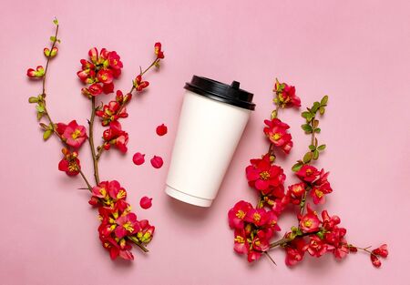 Coffee or tea paper cup, spring branches of red flowers on pink background top view flat lay copy space. Take away coffee cup, mockup. Spring coffee concept, layout for design. Spring flowering.の写真素材