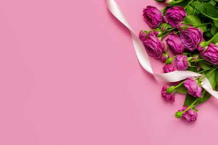 Flat lay flowers composition. Pink rose flowers and colorful holiday ribbons on pink background top view copy space. Greeting card for Birthday Womens or Mothers Day, March 8, Valentine's Day, wedding.の写真素材