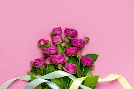 Flat lay flowers composition. Pink rose flowers and colorful holiday ribbons on pink background top view copy space. Greeting card for Birthday Womens or Mothers Day, March 8, Valentine's Day, wedding.の写真素材