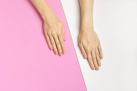 Stylish beautiful gentle manicure. Hands of young woman on pink background top view flat lay copy space. Natural nails, gel polish, self-care, beauty and fashion. Nail care, Beauty salon advertisement.の写真素材