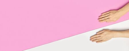 Stylish beautiful gentle manicure. Hands of young woman on pink background top view flat lay copy space. Natural nails, gel polish, self-care, beauty and fashion. Nail care, Beauty salon advertisement.の写真素材