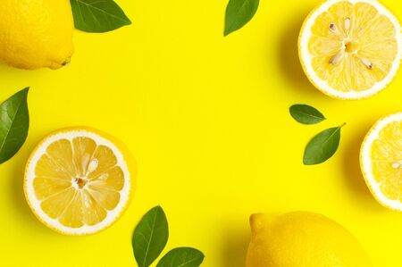 Creative background with fresh lemons and green leaves on bright yellow background. Top view flat lay copy space. Lemon fruit citrus minimal concept vitamin C. Composition with whole, slices of lemons.の写真素材