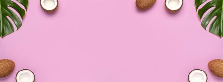 Summer Flat lay background. Frame of tropical leaves and fresh coconut on pink background top view copy space. Healthy cooking. Creative healthy food concept, half of coconut, nature.の写真素材