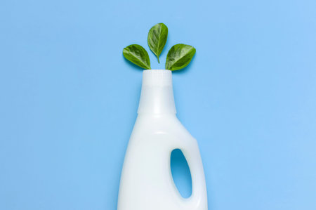 White plastic packaging of laundry detergent, liquid powder, washing conditioner, green leaves on...