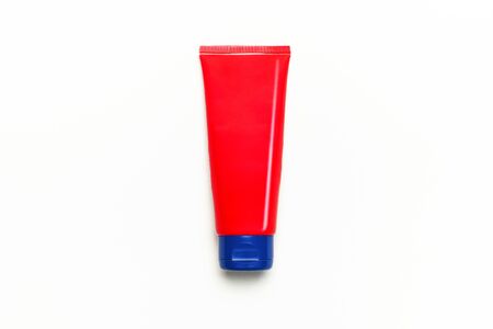 Red clean empty tube of cream or gel for hands, face, body on white background. Flat lay top view copy space. Mock-up of cosmetics spa cream bottles container. Template for design and logo application.の写真素材
