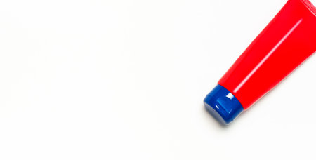 Red clean empty tube of cream or gel for hands, face, body on white background. Flat lay top view...