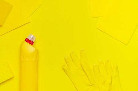 House cleaning concept. Household chemicals, disinfectant, bleach, antibacterial gel, yellow rubber gloves, sponge, rags on yellow background. Flat lay top view copy space. Cleaning accessories.の写真素材