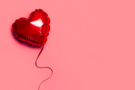 Love concept. Red balloon in the shape of heart on pink background top view flat lay copy space. Holiday Object, Birthday, Valentine's Day, Wedding. Party decoration. Greeting card.の写真素材