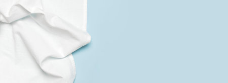 White crumpled natural cotton fabric on delicate blue background top view flat lay with copy space. Natural linen background. Eco textiles. White Fabric texture. Fabric backdrop.の写真素材