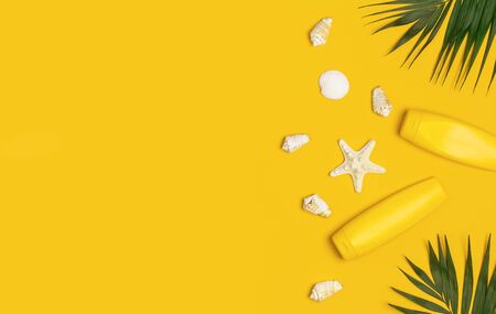 Yellow bottles of sunscreen cream, tropical palm leaves, shells, starfish on yellow background top view flat lay copy space. Sun protection Summer background vacation travel concept Summer cosmetics.の写真素材